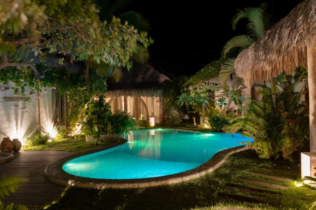 Piscina iluminada à noite entre o deque e os bangalôs
